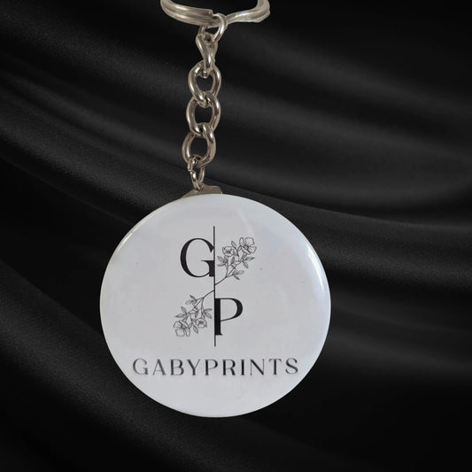 Porte-clé promotionnel blanc à l'effigie de GabyPrints sur tissus noir – White branded keychain featuring GabyPrints on black fabric